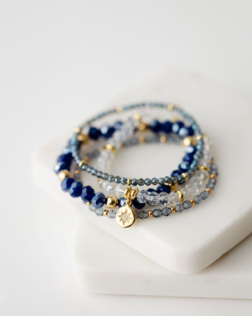 set of four blue and clear beaded bracelets with gold accents 