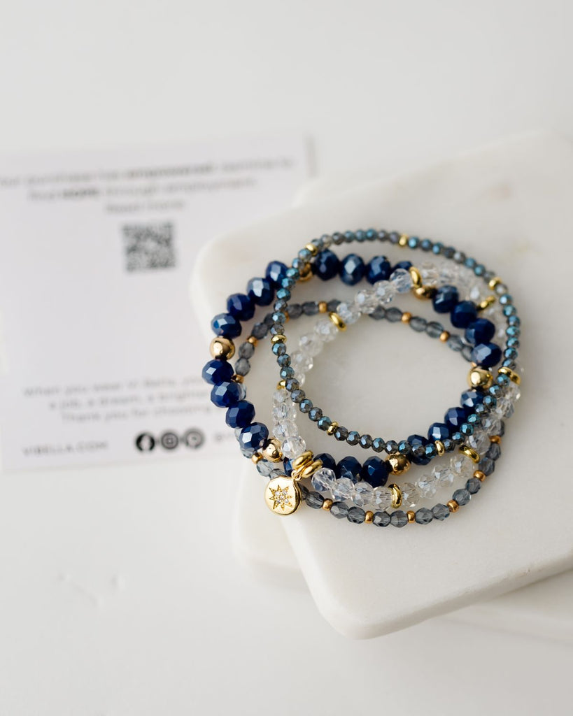 set of four blue and clear beaded bracelets with gold accents