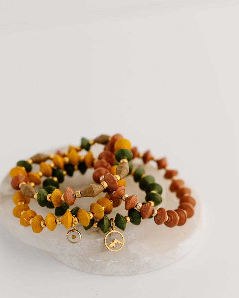 recycled paper bead bracelet set in fall colors of orange, olive green, mustard, and brown, with mustard seed charm and mountain charm